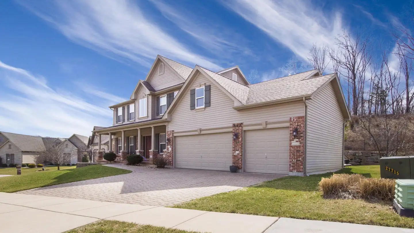 A two-storey home with tan siding, brick accents and a three-car garage