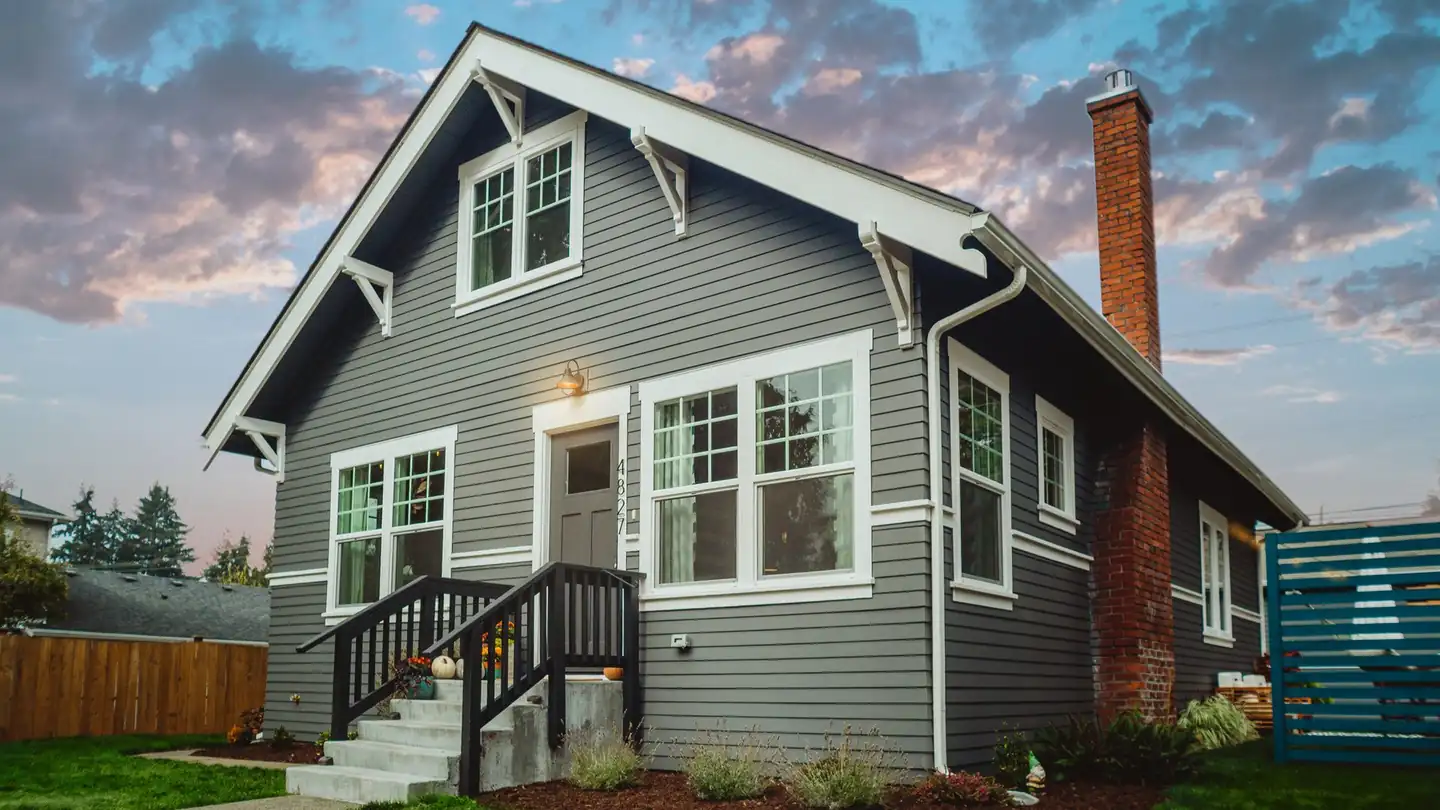 A home clad in slate-grey lap siding with white trim and a brick chimney