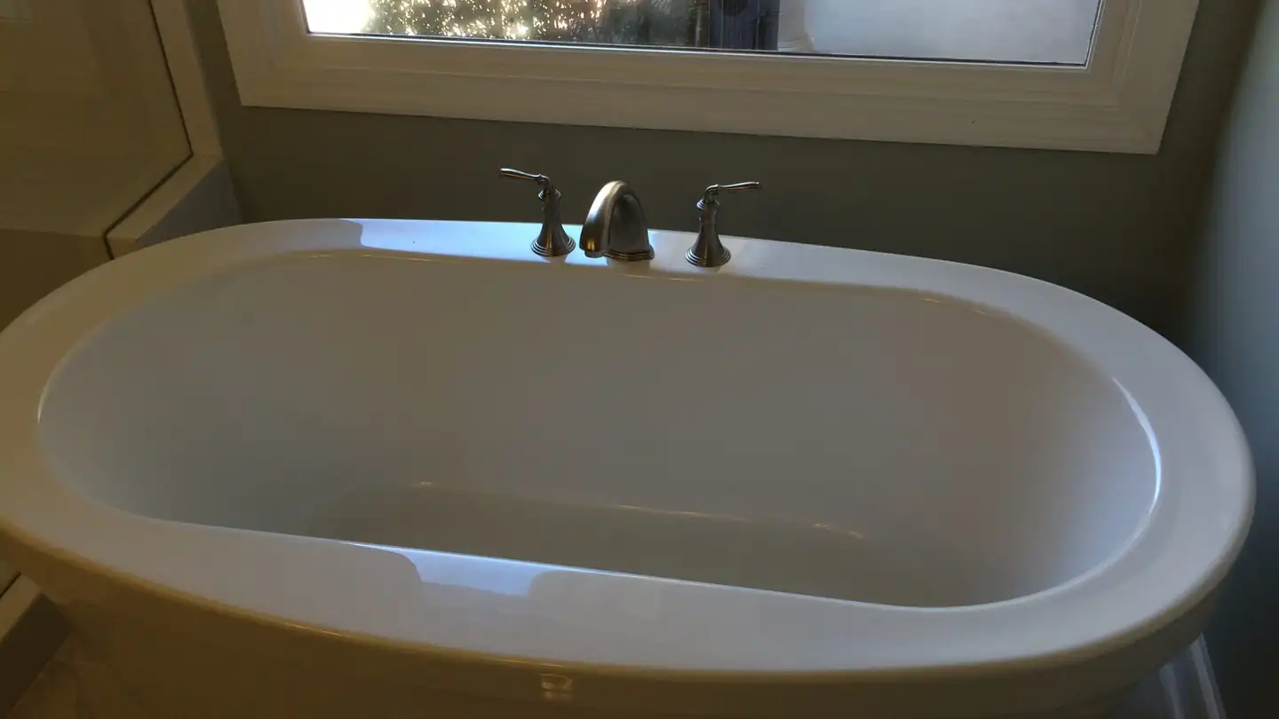 A renovated bathroom with a soaking tub set beneath a window