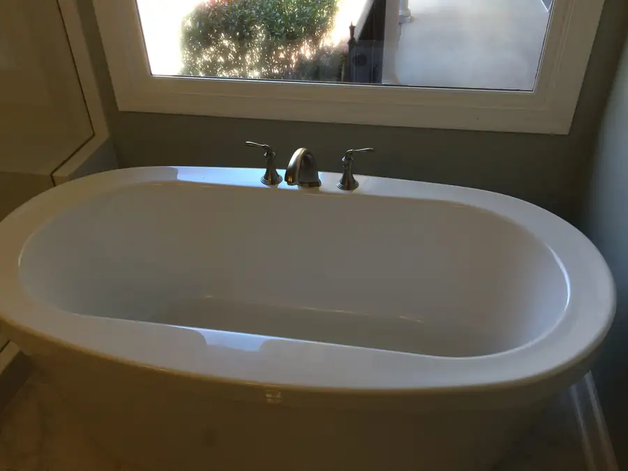 A renovated bathroom with a soaking tub set beneath a window