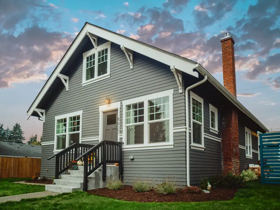 A home clad in slate-grey lap siding with white trim and a brick chimney