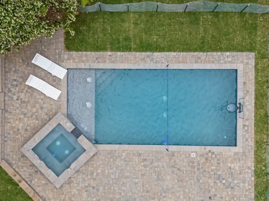 Overhead view of a rectangular pool and square spa set in a paver deck