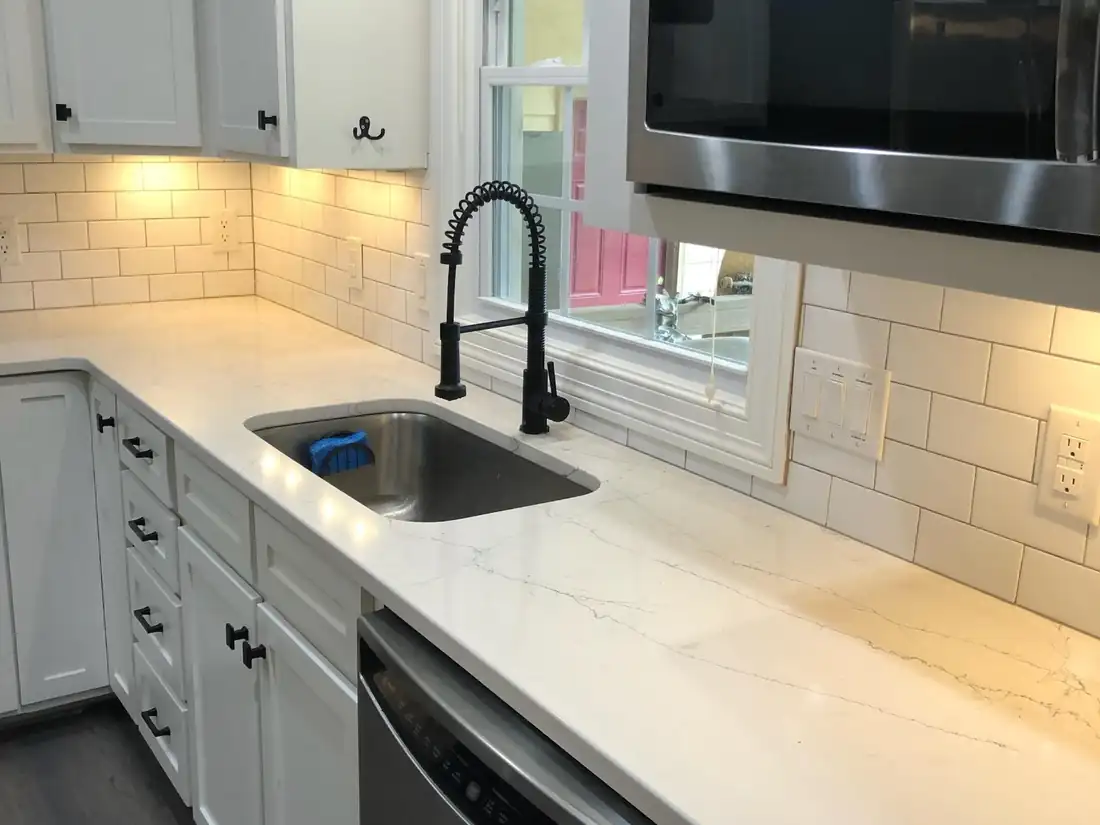 The finished kitchen with white shaker cabinets, quartz counters and a subway-tile backsplash
