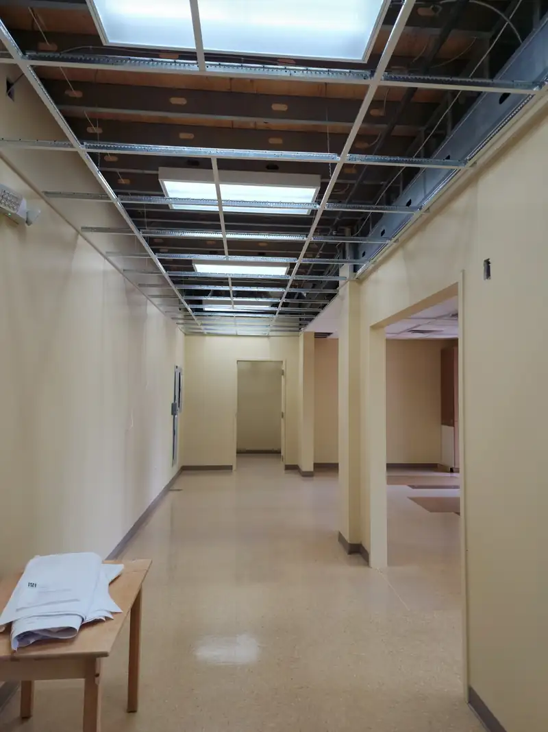 A corridor during an upfit with the ceiling opened and services exposed